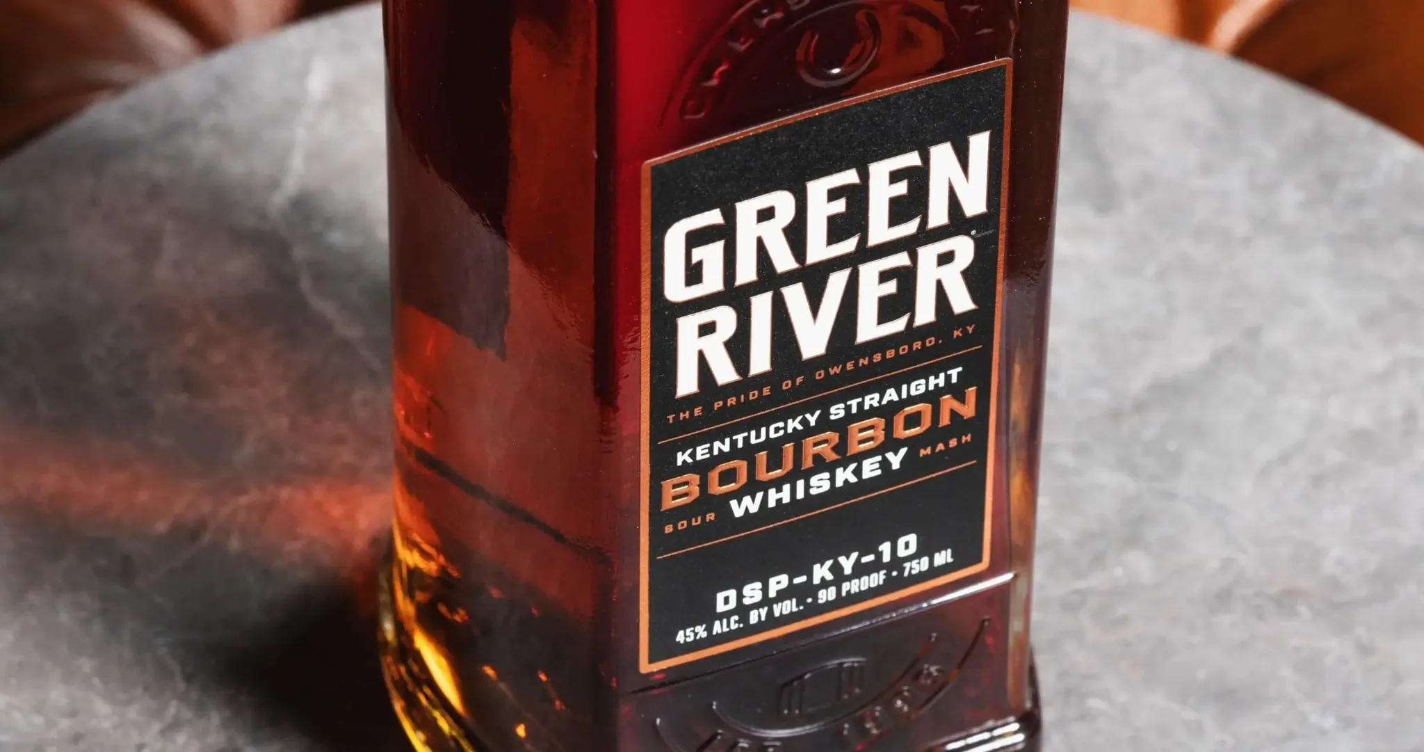 Green River Kentucky Straight Bourbon Whiskey bottle with red label on gray surface